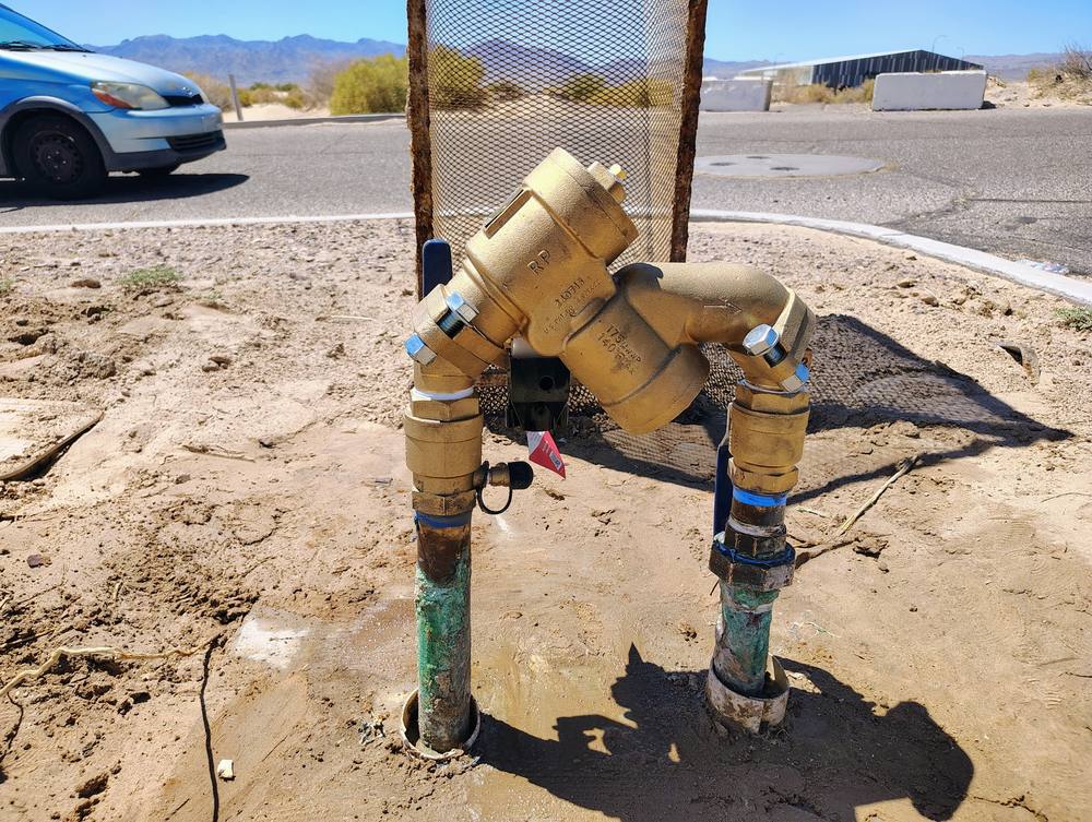 Brass reduced-pressure backflow assembly newly installed on two risers at a commercial site.