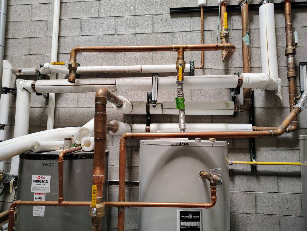 Commercial storage tank and water heater with copper supply, return and recirculation piping.