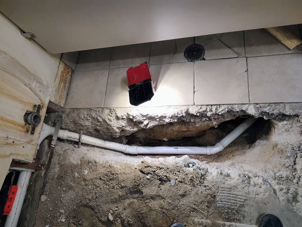 Tile floor opened up with a new PVC drain line run through the trench beneath the slab.