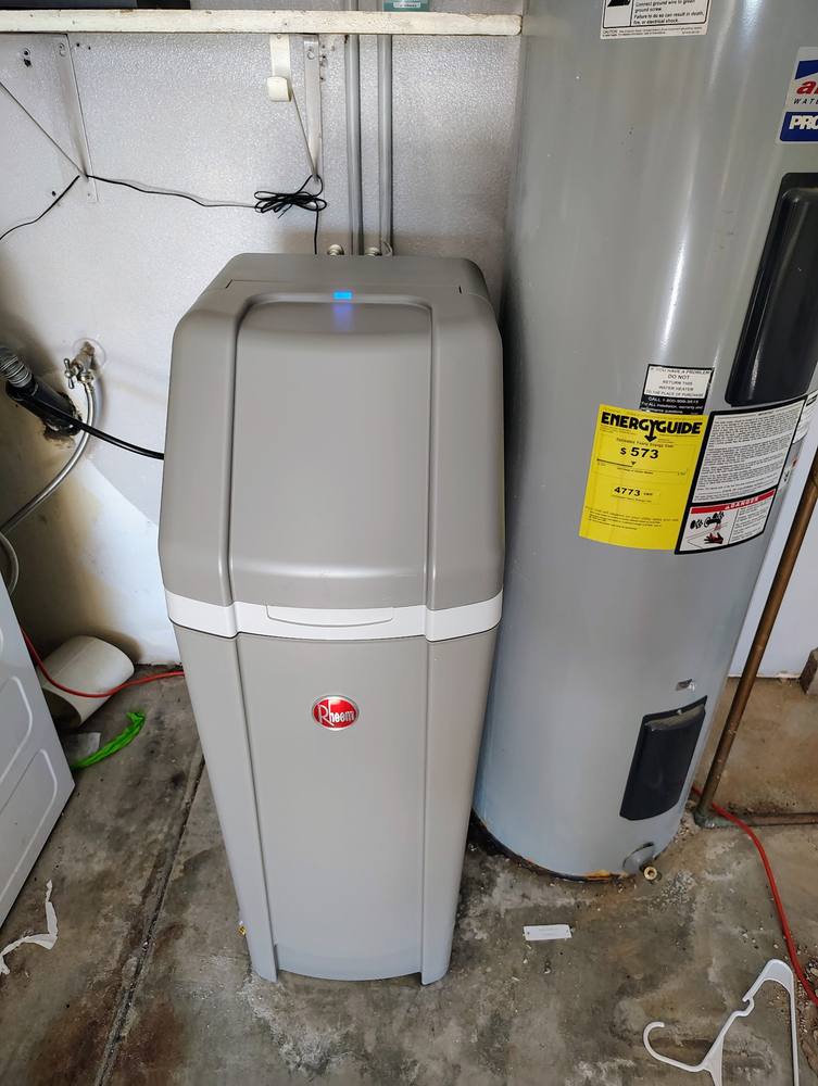 Rheem water softener installed beside a residential water heater in a garage.
